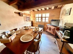 a dining room with a wooden table and a television at Le Logis du Martray, maison historique in Lamballe Armor +17 photos