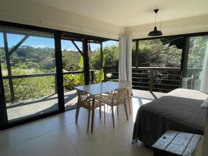 a bedroom with a bed and a table and a balcony at Casa Fluila in Praia do Rosa