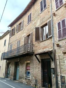 an old brick building with a balcony on a street at La Terrazza sul Lago in Panicale