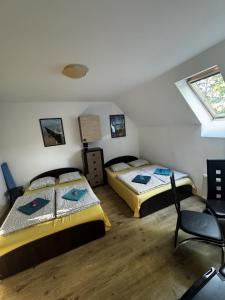 a bedroom with two beds and a chair in it at ahoj PRZYLESIE in Pobierowo