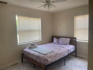 a bedroom with a bed with a fan and two windows at Bungalow Bleu in St. Petersburg