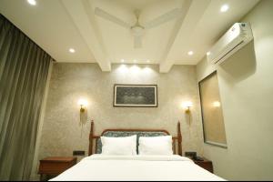 a bedroom with a bed with white sheets at hotel manjushree in Pachmarhī