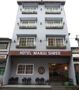 a hotel manu entrance with chairs in front of a building at hotel manjushree in Pachmarhī