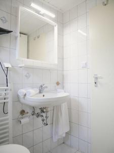 a white bathroom with a sink and a mirror at Hafen Bungalow in Kirchdorf +10 photos