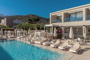 a pool with chairs and umbrellas next to a building at Meramaglia Hotel in Malia