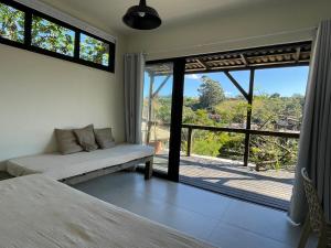 a living room with a couch and a large window at Casa Fluila in Praia do Rosa