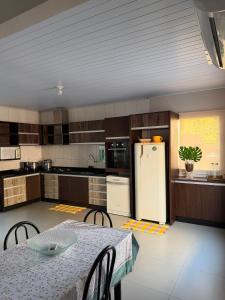 a kitchen with a table and a white refrigerator at Casa completa 3 quartos in Sinop