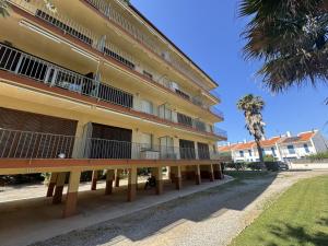 a large yellow building with balconies and a palm tree at Mare Nostrum 143 in Torroella de Montgrí