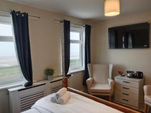 a bedroom with a bed and a chair and windows at 262 Ocean Manor in Blackpool