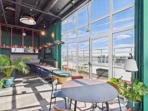 a room with tables and chairs and large windows at Hife Vélizy in Vélizy-Villacoublay