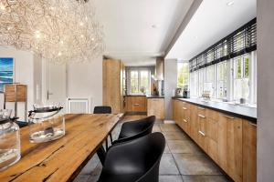 a dining room with a large wooden table and black chairs at Reethus Nordstil in Borgsum +23 photos