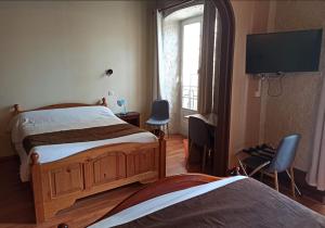a bedroom with two beds and a flat screen tv at Logis Hotel Restaurant La Chaumière in Tournon-sur-Rhône