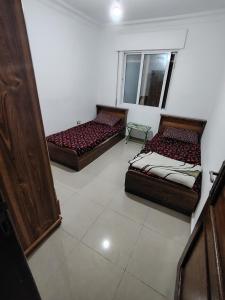 ein Zimmer mit drei Betten und einem Fenster in der Unterkunft شقة ريماس in Irbid