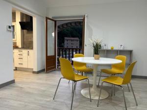 a dining room with a table and yellow chairs at Cal Botey in Ripoll
