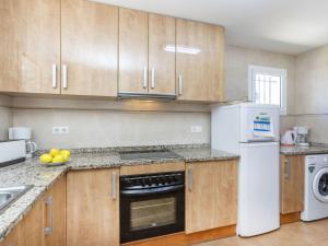 a kitchen with wooden cabinets and a white refrigerator at Holiday Home Bretos by Interhome in Fonts +16 photos