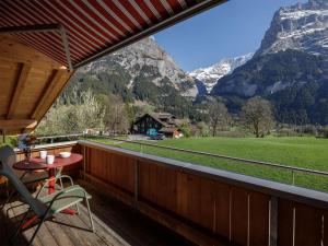 a balcony with a table and a chair and mountains at Apartment Chalet Almisgässli by Interhome in Grindelwald