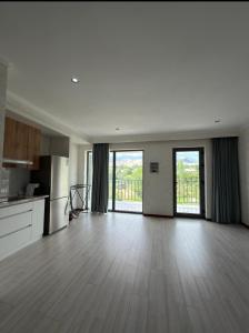 an empty living room with wooden floors and windows at Novel Hotel&Apartaments in Korumdy
