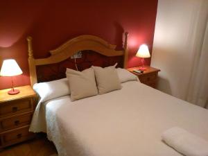 1 dormitorio con 1 cama blanca grande y 2 lámparas en Casa Rural La Esmeralda, en Navarredonda de Gredos