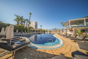 a pool with lounge chairs and umbrellas at a resort at Anonymous Beach Hotel (Adults 16+) in Ayia Napa