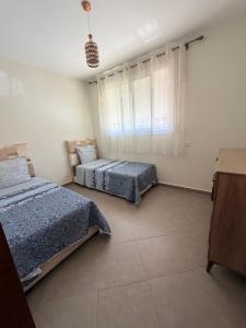 a bedroom with two beds and a window at Location meublée Martil in Martil
