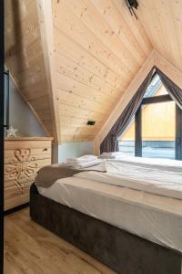 a large bed in a room with a large window at Apartamenty Premium VIEW JACUZZI & SAUNA in Kościelisko
