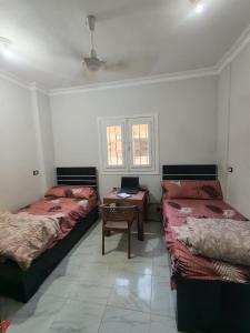 a room with three beds and a table and a window at Um yousef house in Alexandria