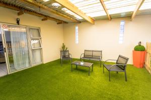 a room with chairs and a table and grass at Meerkat Manor Self-Catering & Accommodation Windhoek in Windhoek