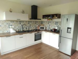 a kitchen with white cabinets and a refrigerator at La mouche de mai in Fécamp