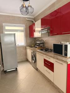 a kitchen with red cabinets and a stainless steel refrigerator at Location meublée Martil in Martil