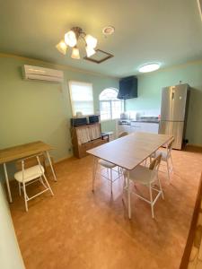 a kitchen with a table and chairs and a refrigerator at Guest House SOL in Hiraisomachi