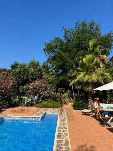 a woman sitting on a chair next to a swimming pool at La Finca Blanca in Alora +133 photos