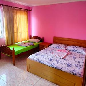 two beds in a room with pink walls at Adventure Beach Hostal in Durrës