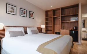 a bedroom with a large white bed and wooden shelves at Hostal del Bosque in Ushuaia
