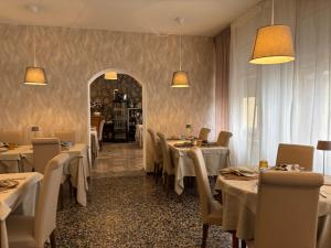 a restaurant with white tables and chairs and a mirror at Hotel Regina Yeti Bistrot in Sestola