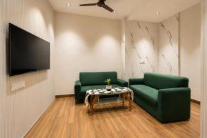 a living room with two green chairs and a table at Subhash Hotel in Prayagraj