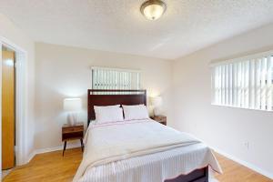 a white bedroom with a bed and two windows at Serenity House - 1006 Ave 26th in Vero Beach