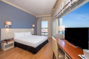 a hotel room with a bed and a desk with a television at Hotel Agamenón in Es Castell