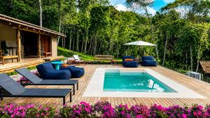 a pool on a deck with chairs and an umbrella at Celeiro in Campina Grande do Sul