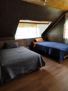 a attic bedroom with two beds and a window at Yanesh Haus habitaciones Oxapampa in San Antonio