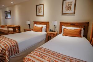 a bedroom with two beds and a chair and a table at Hostal del Bosque in Ushuaia +28 photos