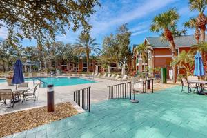 a swimming pool with tables chairs and umbrellas at Cypress Cove 111 in Melbourne