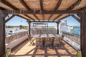 a patio with a table and chairs on a balcony at Rivara Rooftop By ALGARTUR in Cabanas de Tavira