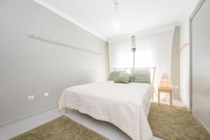 a white bedroom with a bed and a window at Rivara Rooftop By ALGARTUR in Cabanas de Tavira