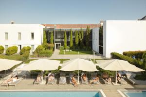 a group of people sitting in chairs under umbrellas by a pool at M'AR De AR Aqueduto in Évora