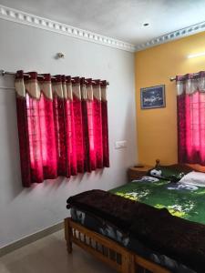 a bedroom with two beds and red curtains at VS valley view resorts in Kotagiri