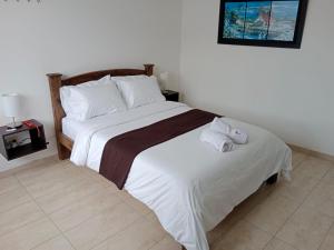 a bedroom with a large bed with towels on it at Hotel La Palmita in Pacho +3 photos