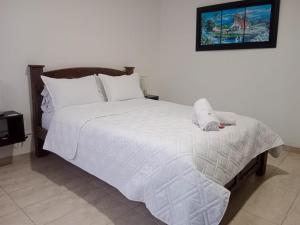a bedroom with a large white bed with white sheets at Hotel La Palmita in Pacho