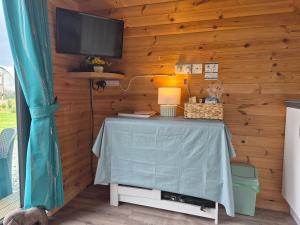 a room with a table with a television on a wooden wall at An Gearasdan in Eoropie