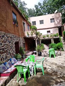 a patio with green chairs and tables and a building at Gite Oussalem timichi in Timichchi +10 photos
