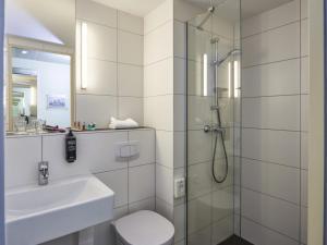 a bathroom with a shower and a toilet and a sink at Ibis Budget Singen 24h geöffnet in Singen +32 photos